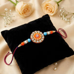 Circular Crystal Encrusted Floral Emblem Orange Accent Rakhi